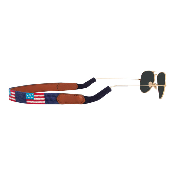 Back view of handstitched American Flag needlepoint sunglass strap showing American Flags against a navy blue background with sturdy cotton covered silicone ear connectors and a soft leather backing