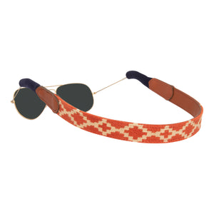 Argentine Needlepoint Sunglass Strap showing an Argentinean themed gaucho pattern in burnt orange and light tan. Sunglass straps have a full grain leather backing and secure cotton wrapped earpiece connectors for a secure grip.