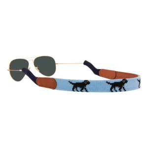Black Labrador themed needlepoint sunglass strap showing a black lab design against a light blue background with sturdy cotton covered silicone ear connectors and a soft leather backing
