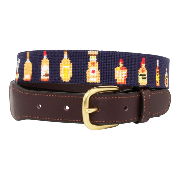 Bourbon Bottle Needlepoint Belt with navy blue background showing a repeating pattern of popularbourbon bottles around the belt. Belt has a brass buckle and full grain leather backing and strap.