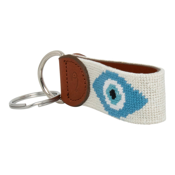 Hand-stitched evil eye needlepoint keychain showing an evil eye on both sides against a stone colored background and leather backing.  Stainless steel D-ring and keyring.