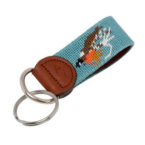 Hand-stitched Fly Fishing needlepoint keychain showing a fly fishing trout fly pattern on both sides against a light blue background and leather backing.  Stainless steel D-ring and keyring.