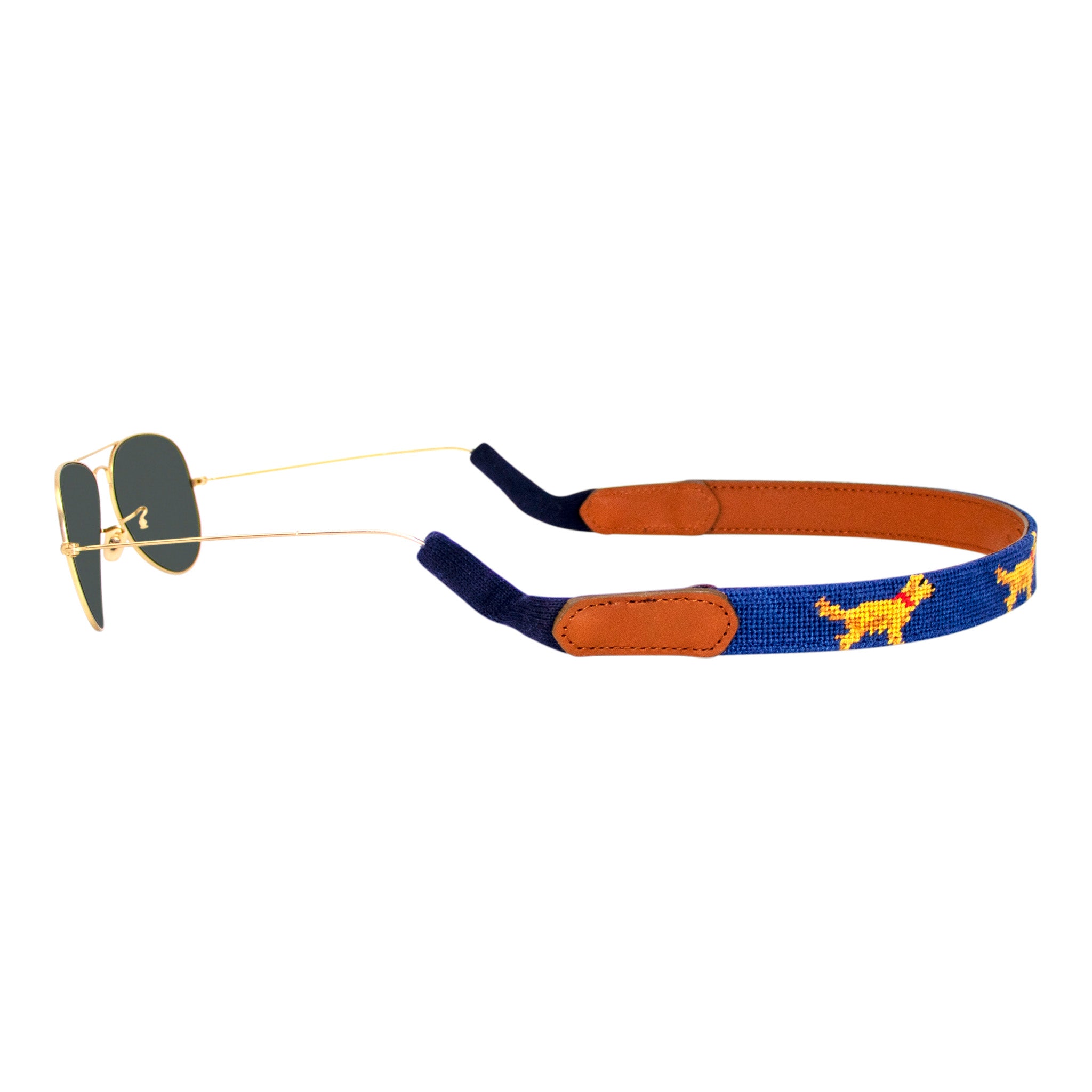 Golden retriever themed needlepoint sunglass strap showing a golden retriever design against a navy blue background with sturdy cotton covered silicone ear connectors and a soft leather backing