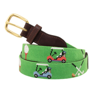 Golfing Needlepoint Belt with light green background showing a repeating pattern of teed gold ball, crossed gold clubs, and colorful golf carts. Belt has a brass buckle and full grain leather backing and strap.