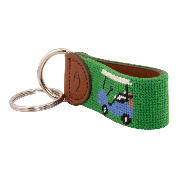 Hand-stitched golfing themed needlepoint keychain showing crossed golf clubs on both sides against a green background and leather backing.  Stainless steel D-ring and keyring.