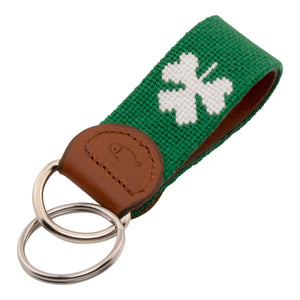 Hand-stitched shamrock needlepoint keychain showing a green shamrock on both sides against a navy blue background and leather backing.  Stainless steel D-ring and keyring.