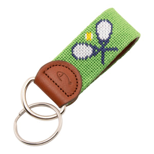 Hand-stitched tennis needlepoint keychain showing crossed tennis racquets on both sides against a green background and leather backing.  Stainless steel D-ring and keyring.