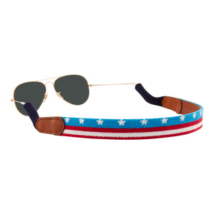 American Flag  banner needlepoint sunglass strap showing the American Flag in banner format across the whole sunglass strap.  The strap has a sturdy cotton covered silicone ear connectors and a soft leather backing