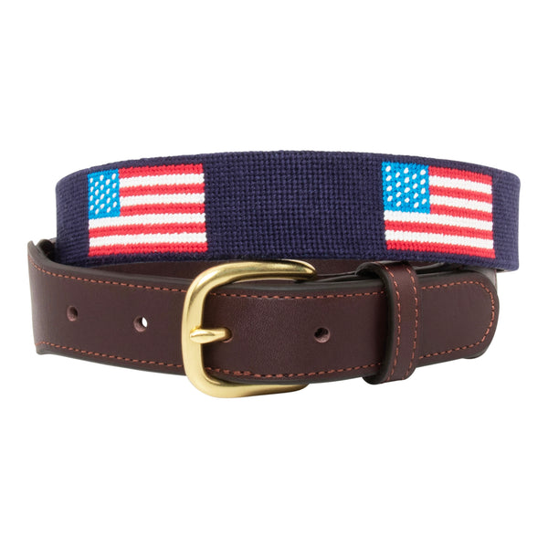 Front view of American Flag Needlepoint Belt with navy blue background and repeating pattern of evenly spaced american flags. Belt has a brass buckle and full grain leather backing and strap.
