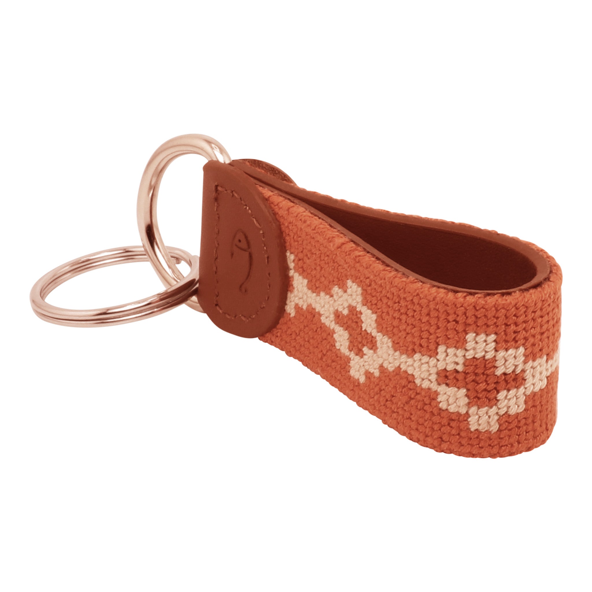 Hand-stitched Argentinian needlepoint key fob with terracotta canvas, cream geometric pattern, and fine-grain leather trim featuring stainless steel key rings.
