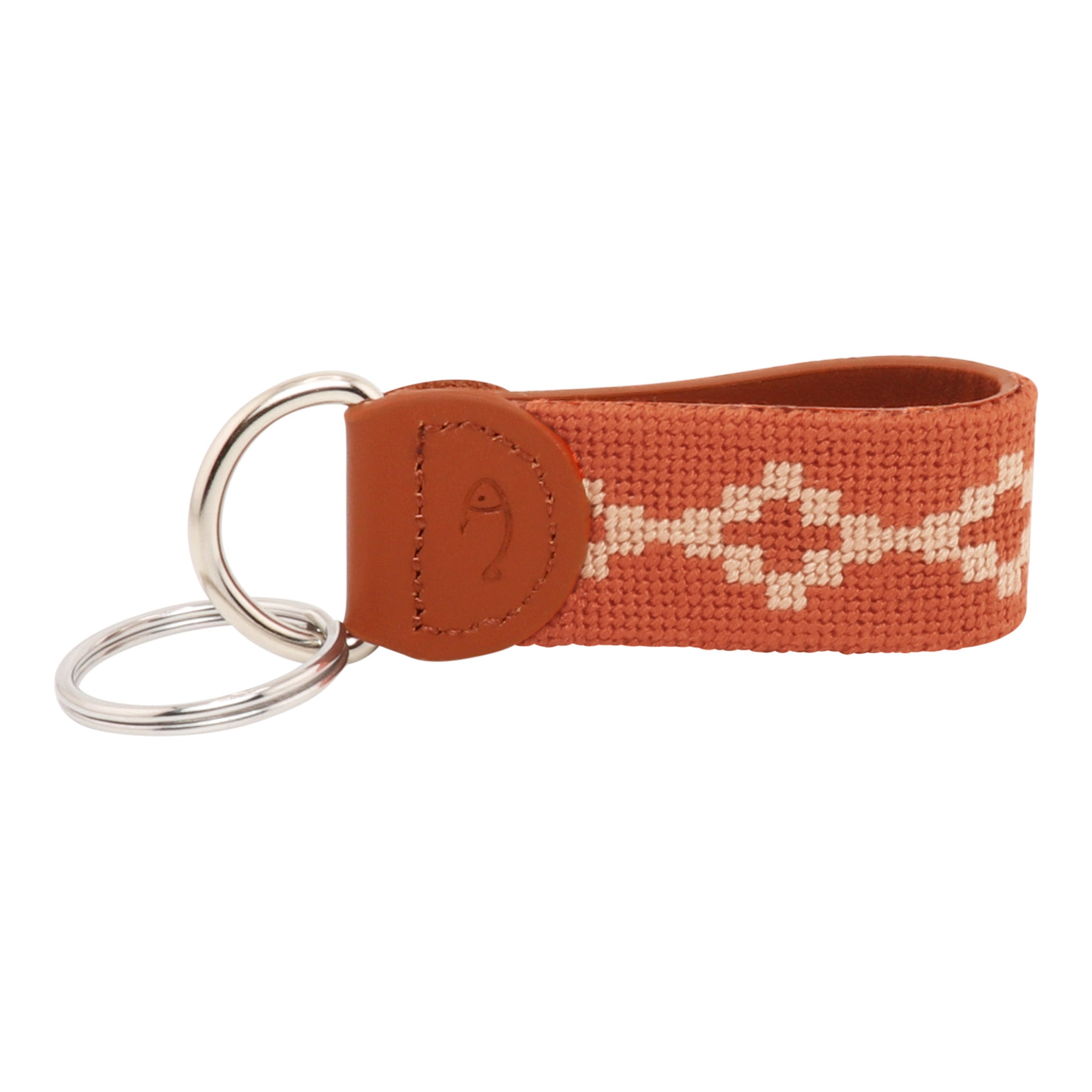 Hand-stitched Argentinian needlepoint key fob with terracotta canvas, cream geometric pattern, and fine-grain leather trim featuring stainless steel key rings.