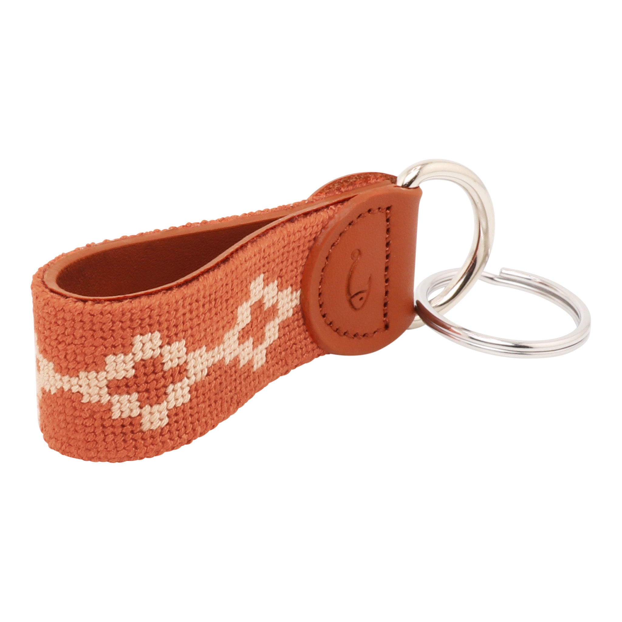 Hand-stitched Argentinian needlepoint key fob with terracotta canvas, cream geometric pattern, and fine-grain leather trim featuring stainless steel key rings.