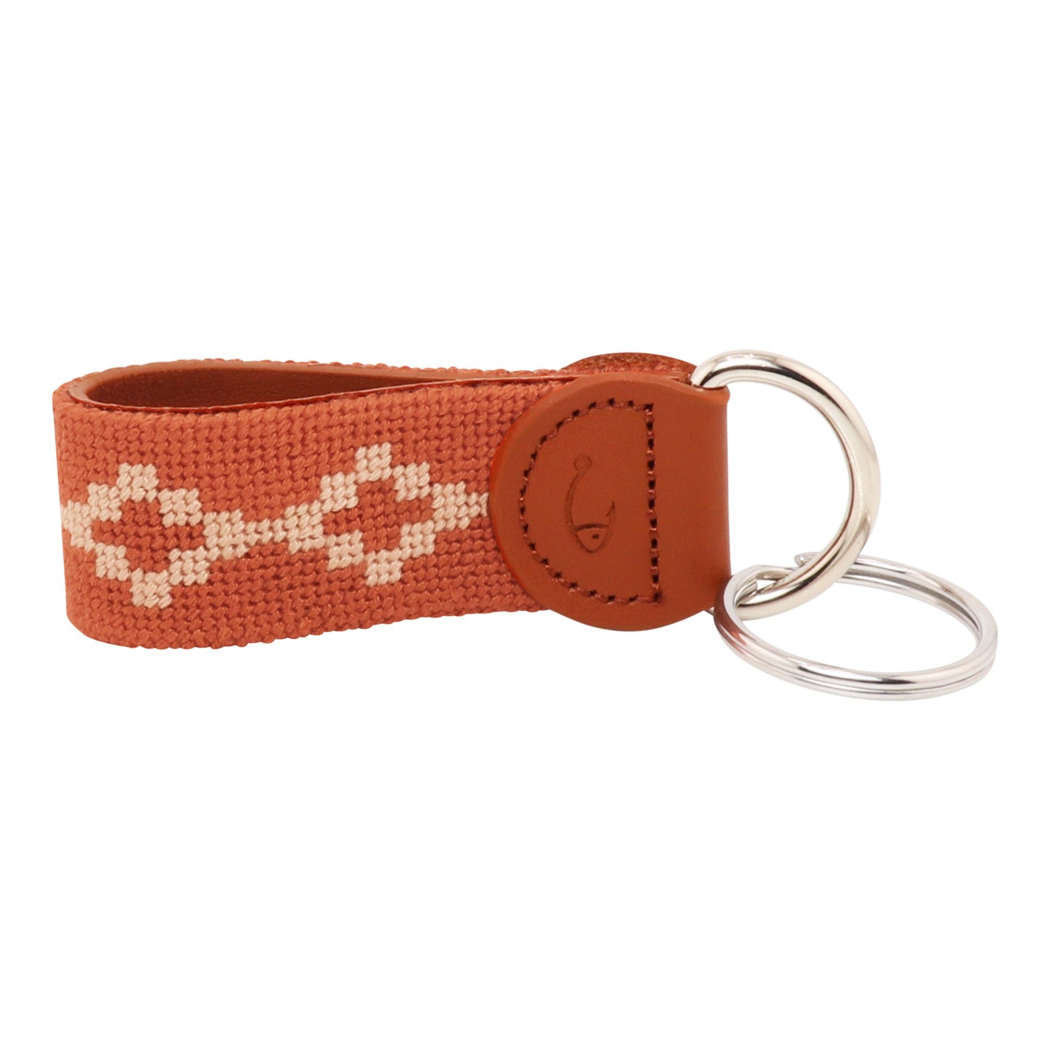 Hand-stitched Argentinian needlepoint key fob with terracotta canvas, cream geometric pattern, and fine-grain leather trim featuring stainless steel key rings.