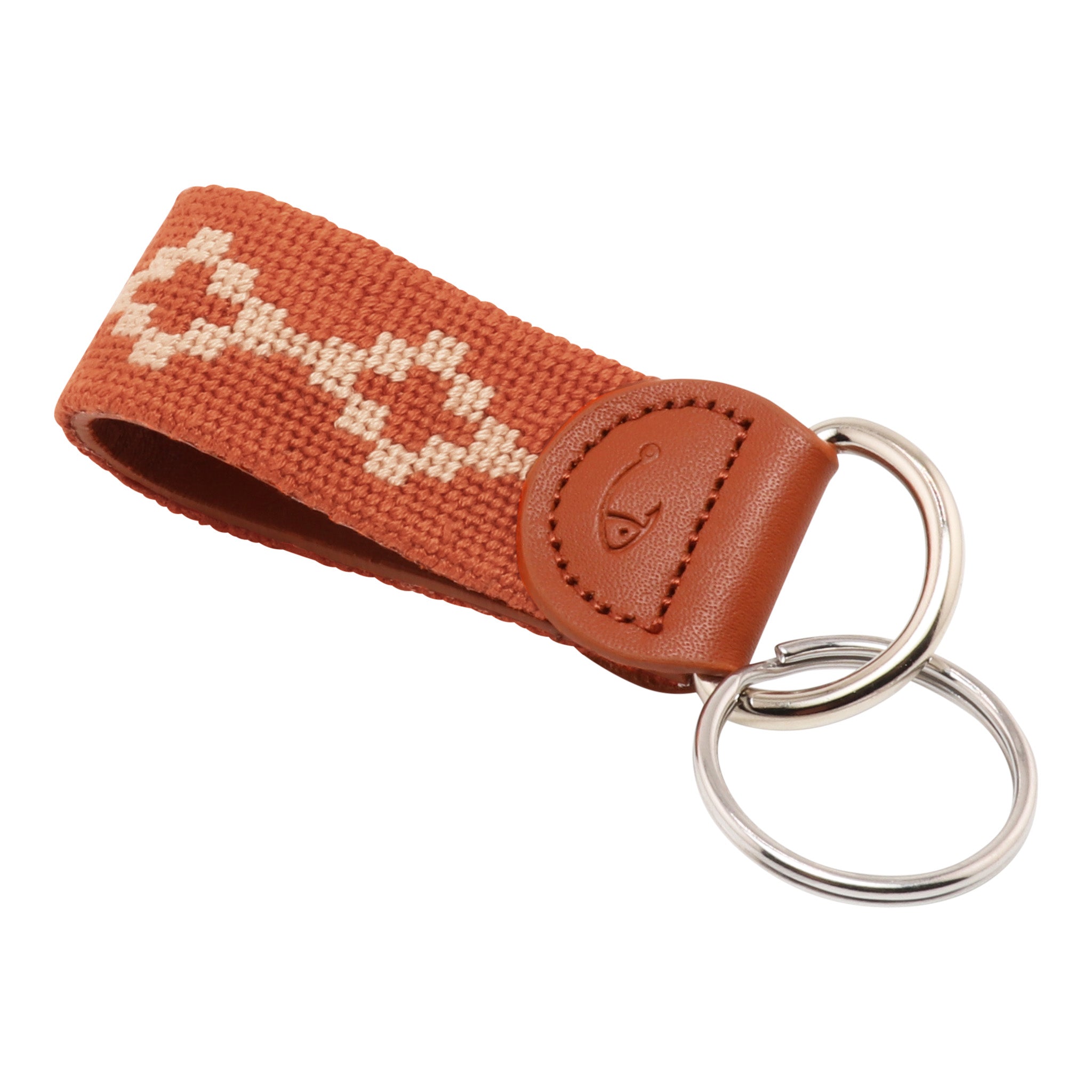 Hand-stitched Argentinian needlepoint key fob with terracotta canvas, cream geometric pattern, and fine-grain leather trim featuring stainless steel key rings.