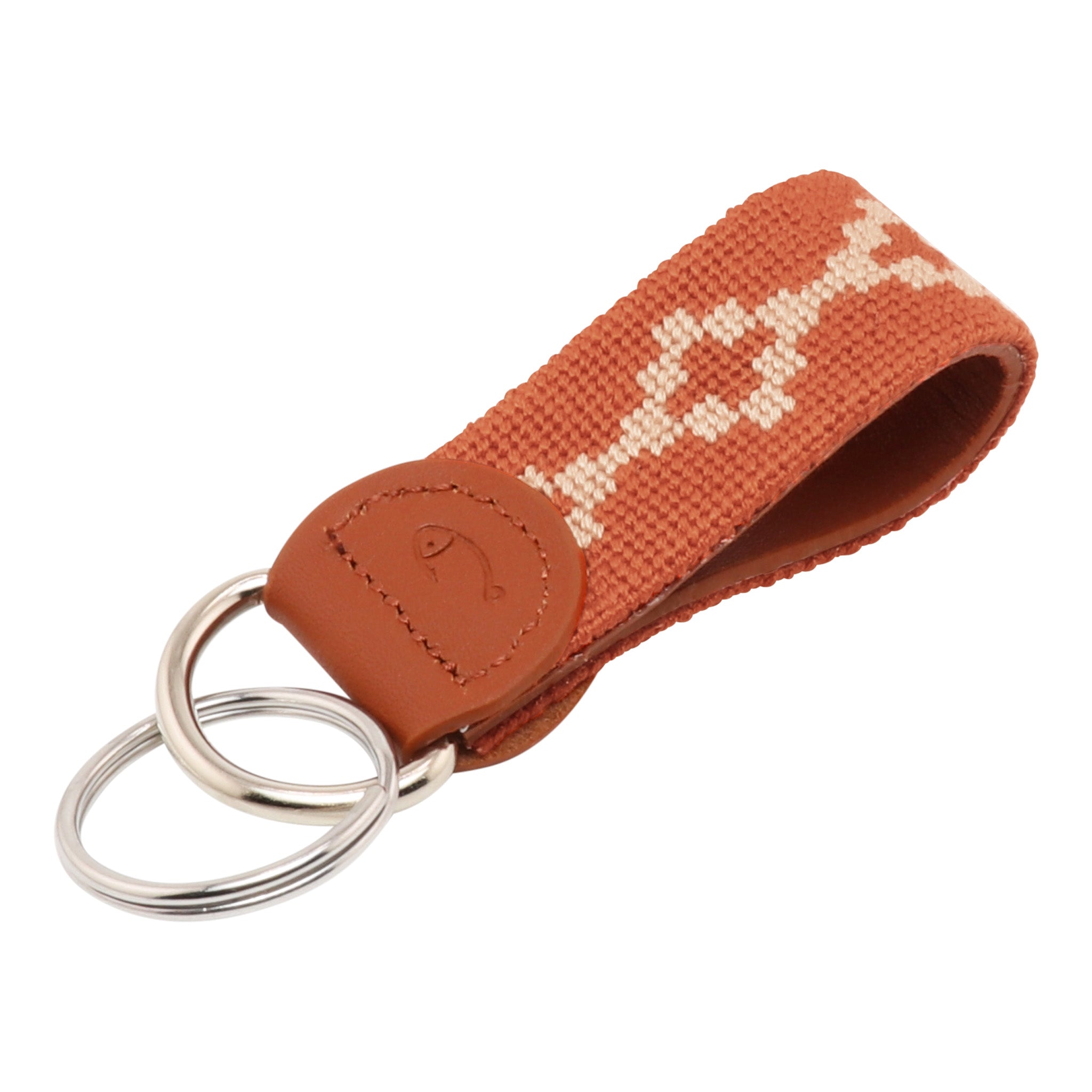 Hand-stitched Argentinian needlepoint key fob with terracotta canvas, cream geometric pattern, and fine-grain leather trim featuring stainless steel key rings.