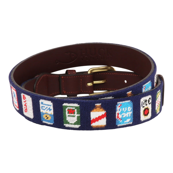 Back view of Beer Can Needlepoint Belt with navy blue background showing a repeating pattern of popular beer cans around the belt. Belt has a brass buckle and full grain leather backing and strap.
