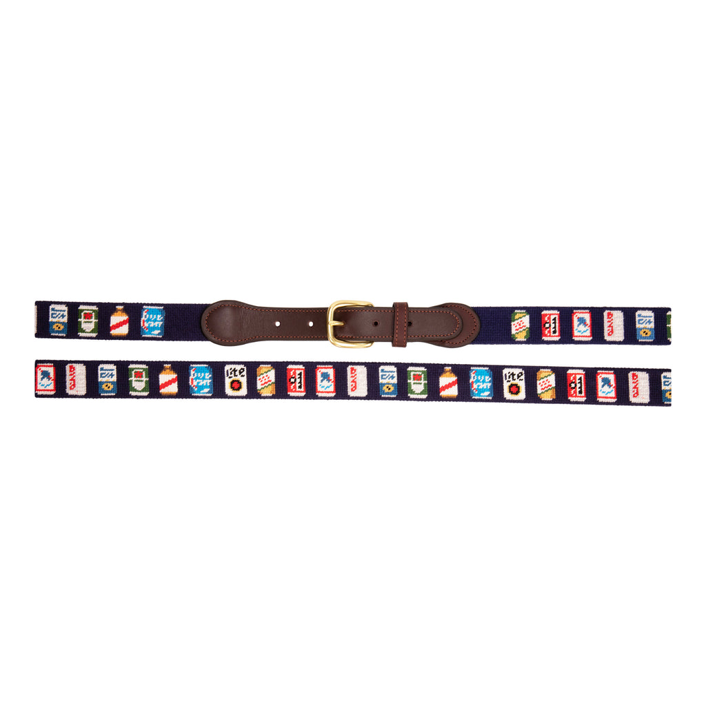 Full view of Beer Can Needlepoint Belt with navy blue background showing a repeating pattern of popular beer cans around the belt. Belt has a brass buckle and full grain leather backing and strap.