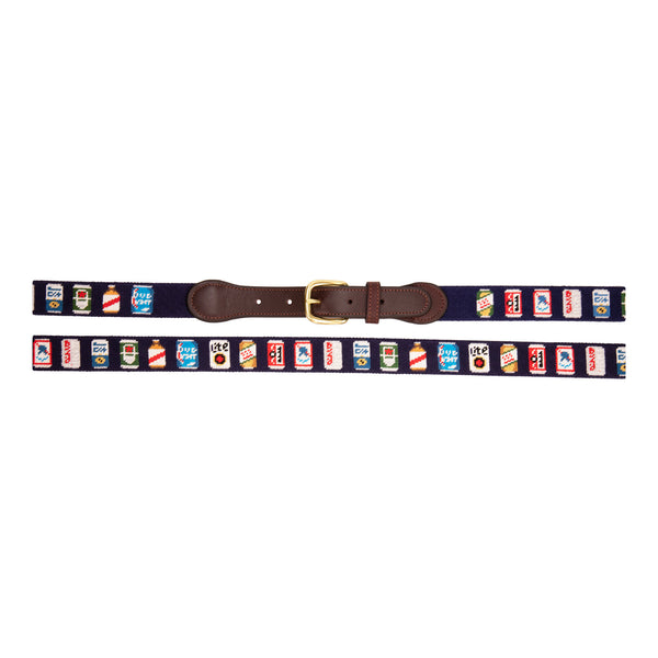 Full view of Beer Can Needlepoint Belt with navy blue background showing a repeating pattern of popular beer cans around the belt. Belt has a brass buckle and full grain leather backing and strap.