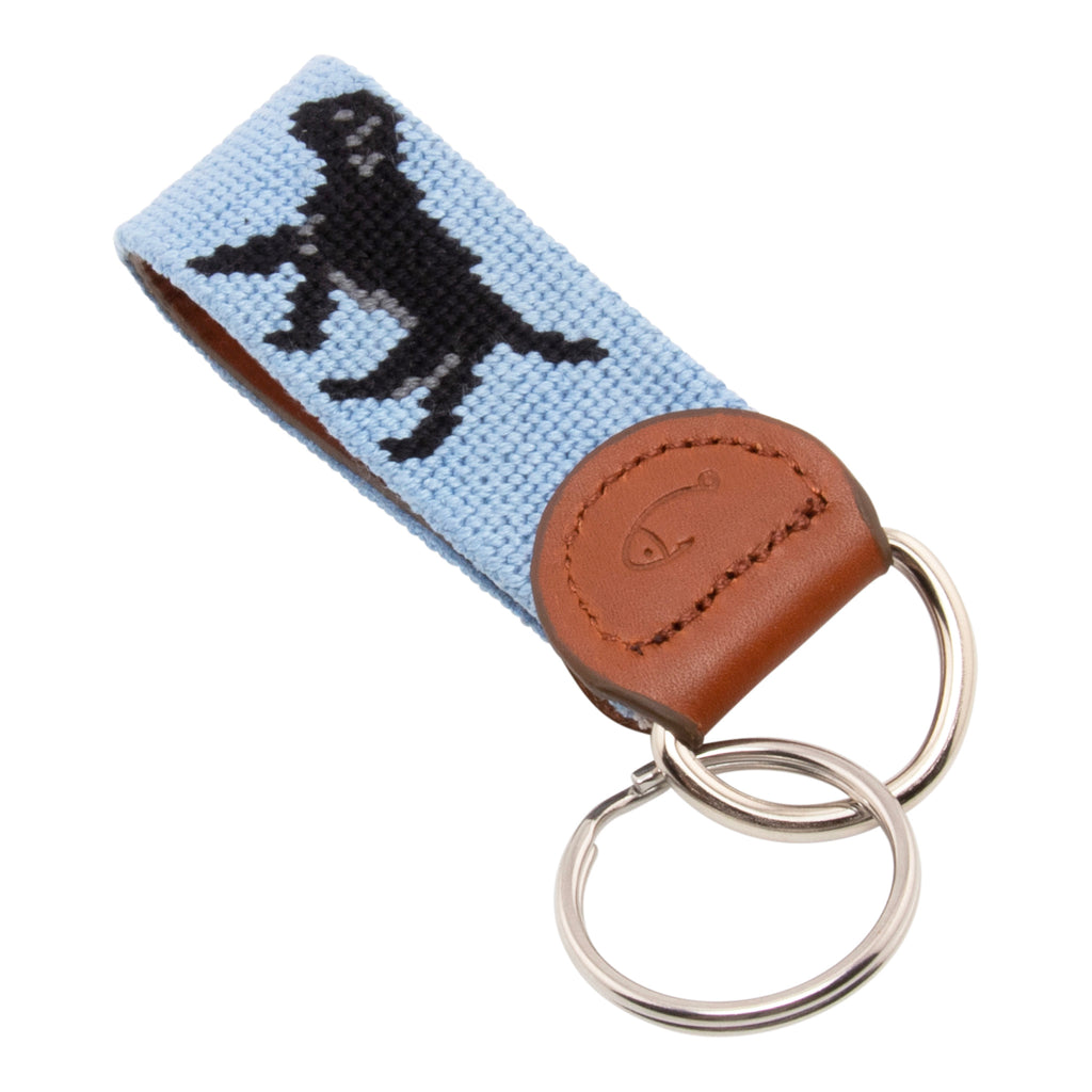 Hand-stitched black Labrador needlepoint keychain showing a black lab on both sides against a light blue background and leather backing.  Stainless steel D-ring and keyring.