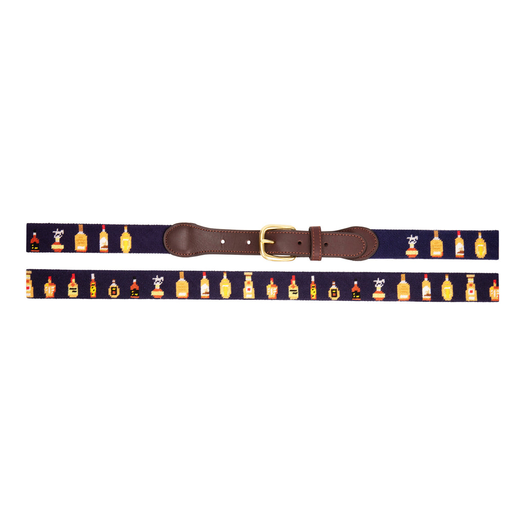 Bourbon Bottle Needlepoint Belt with navy blue background showing a repeating pattern of popularbourbon bottles around the belt. Belt has a brass buckle and full grain leather backing and strap.