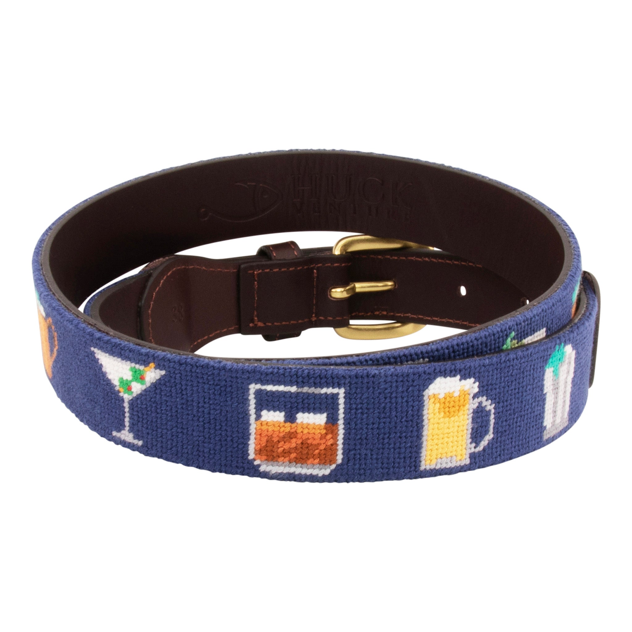 Cocktail Needlepoint Belt with navy blue background showing a repeating pattern of popular cocktails such as a martini, bourbon on the rocks, glass of wine, beer, mint julep around the belt. Belt has a brass buckle and full grain leather backing and strap.