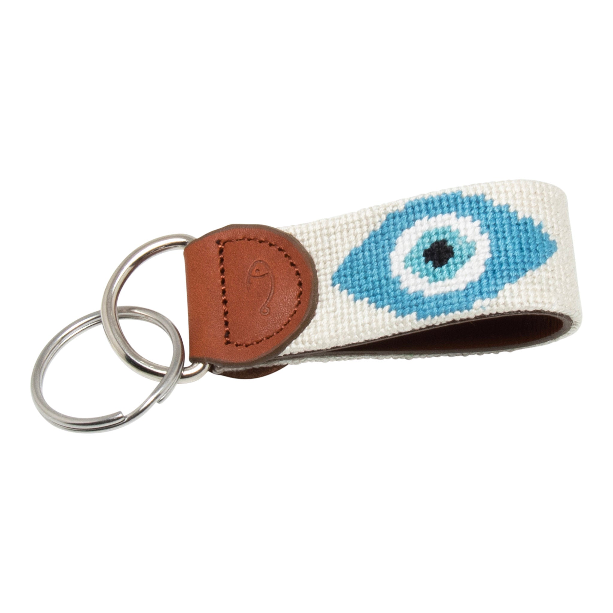 Hand-stitched evil eye needlepoint keychain showing an evil eye on both sides against a stone colored background and leather backing.  Stainless steel D-ring and keyring.