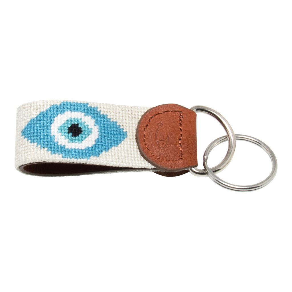 Hand-stitched evil eye needlepoint keychain showing an evil eye on both sides against a stone colored background and leather backing.  Stainless steel D-ring and keyring.