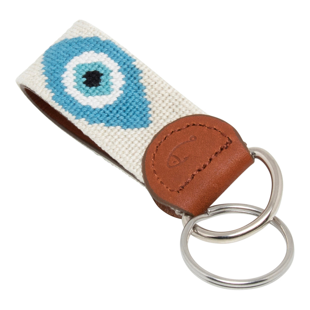 Hand-stitched evil eye needlepoint keychain showing an evil eye on both sides against a stone colored background and leather backing.  Stainless steel D-ring and keyring.