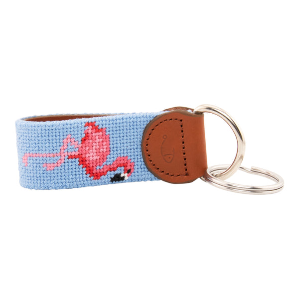 needlepoint keychain showing a pink flamingo on both sides against a light blue background, hand-stitched, leather backing, and stainless steel hardware