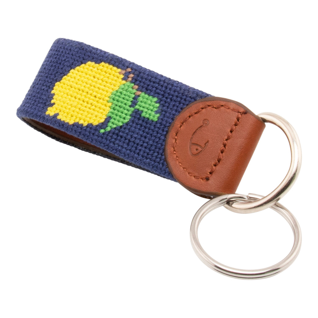 Hand-stitched lemon needlepoint keychain showing a Positano lemon on both sides against a navy blue background and leather backing.  Stainless steel D-ring and keyring.