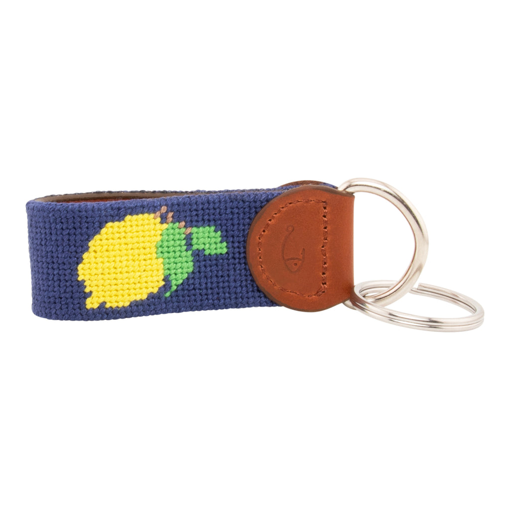 Hand-stitched lemon needlepoint keychain showing a Positano lemon on both sides against a navy blue background and leather backing.  Stainless steel D-ring and keyring.