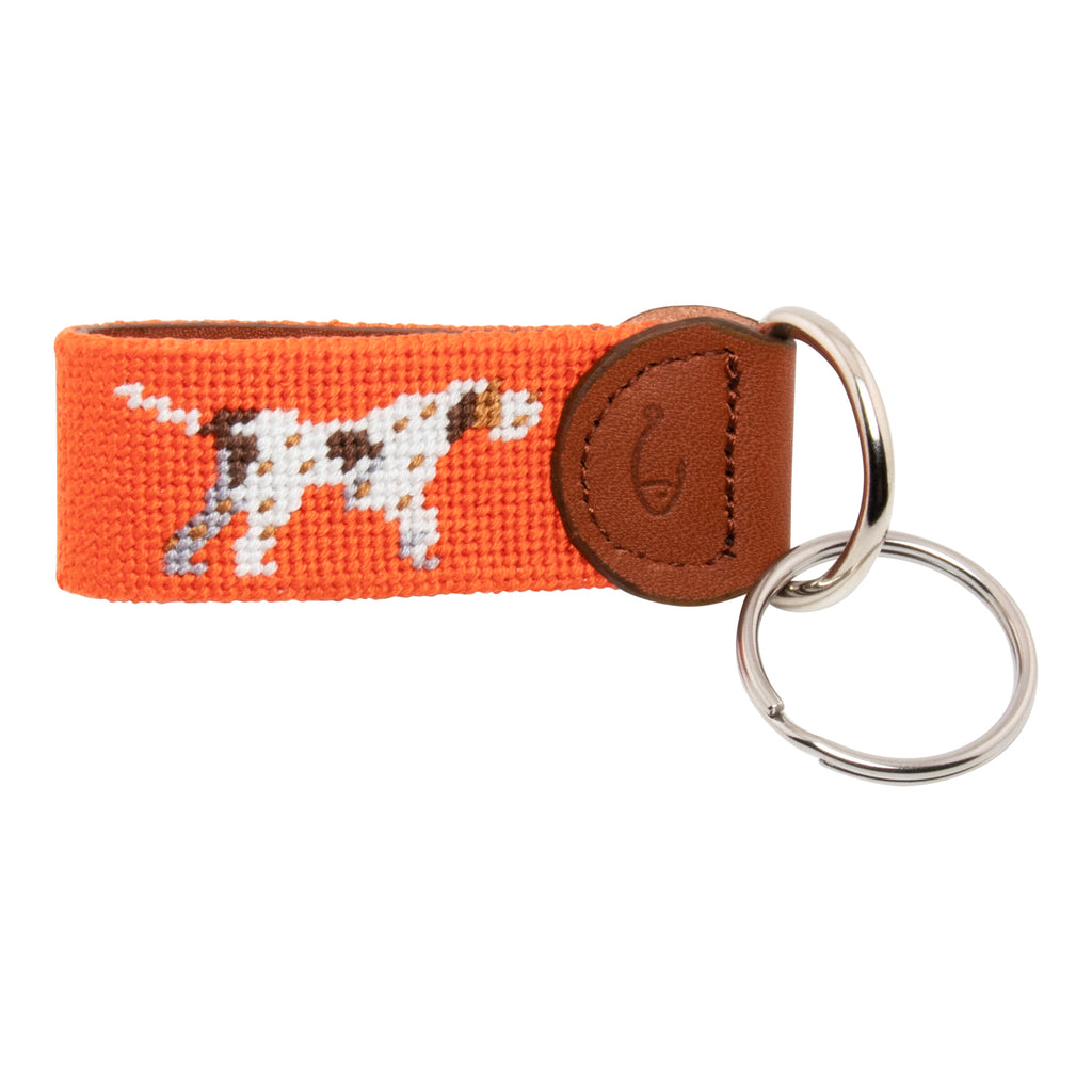 Hand-stitched Pointer Dog needlepoint keychain showing a dog in pointing stance on both sides against a blaze orange background and leather backing.  Stainless steel D-ring and keyring.