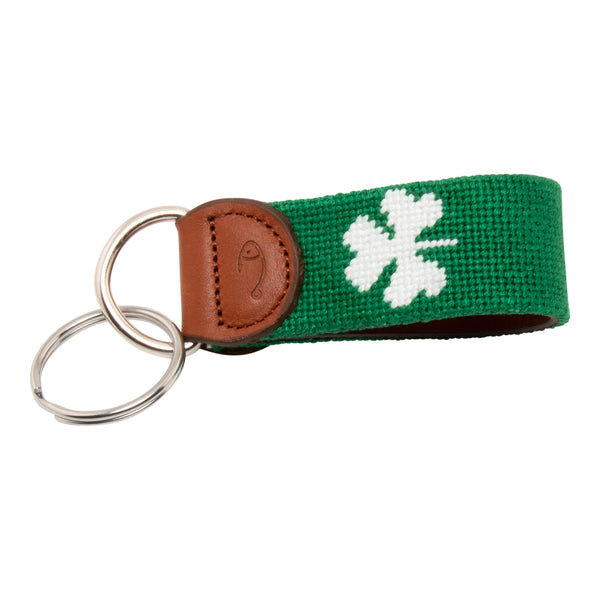 Hand-stitched shamrock needlepoint keychain showing a green shamrock on both sides against a navy blue background and leather backing.  Stainless steel D-ring and keyring.