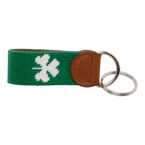 Hand-stitched shamrock needlepoint keychain showing a green shamrock on both sides against a navy blue background and leather backing.  Stainless steel D-ring and keyring.