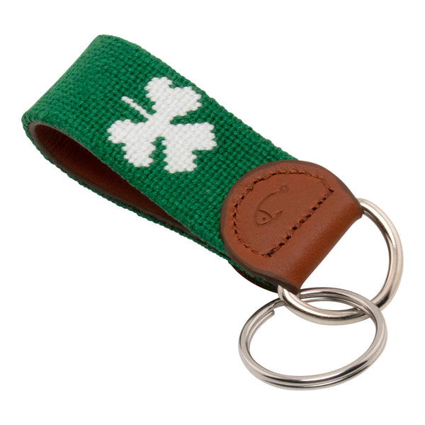 Hand-stitched shamrock needlepoint keychain showing a green shamrock on both sides against a navy blue background and leather backing.  Stainless steel D-ring and keyring.