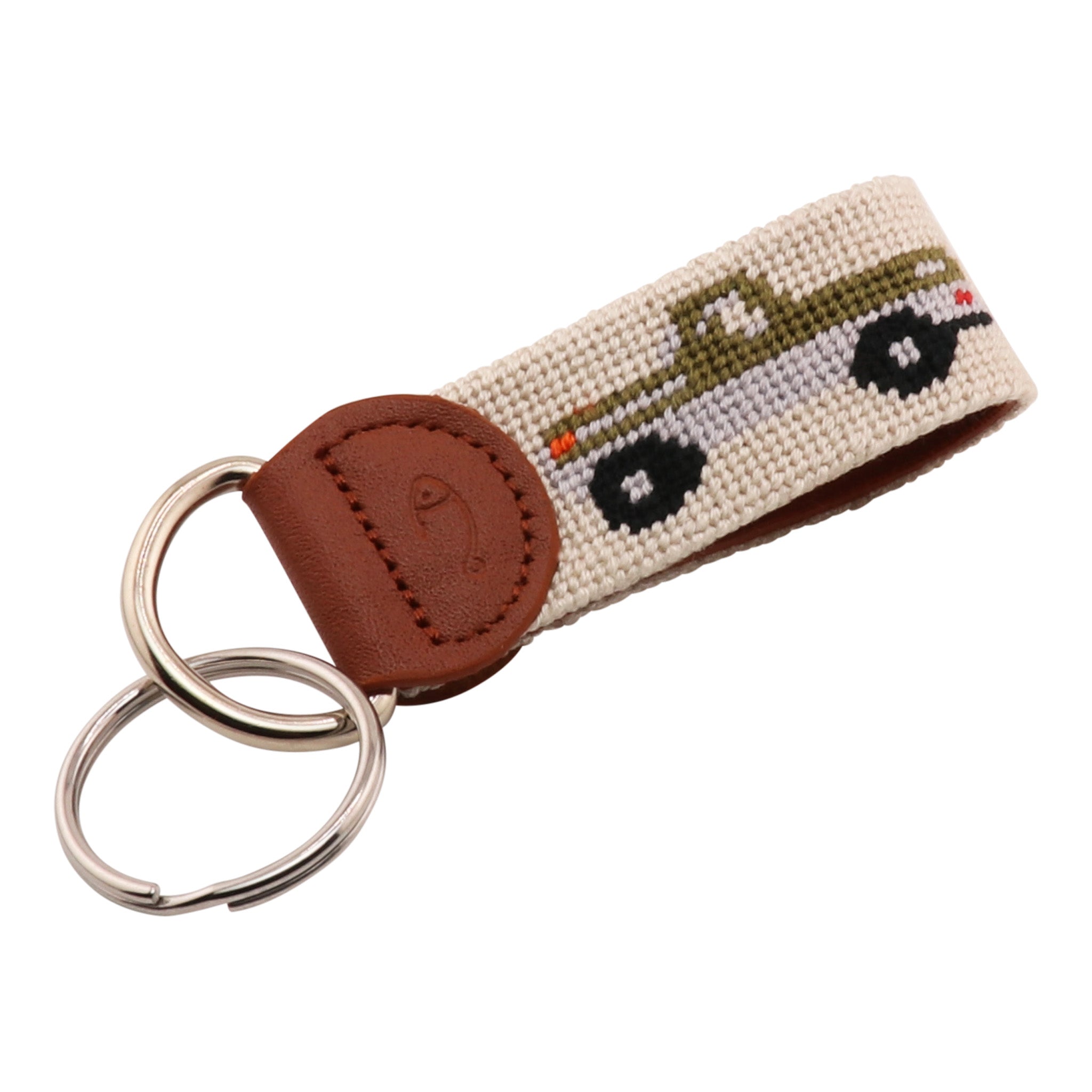 A beige needlepoint key fob with a hand-stitched pickup truck design and a brown leather backing.