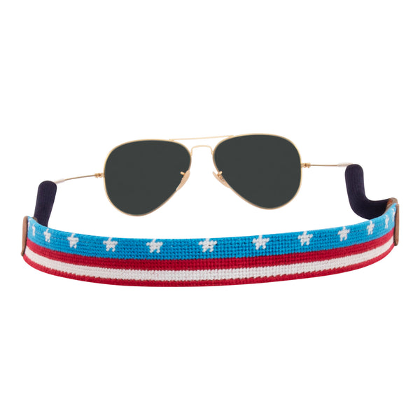 American Flag  banner needlepoint sunglass strap showing the American Flag in banner format across the whole sunglass strap.  The strap has a sturdy cotton covered silicone ear connectors and a soft leather backing